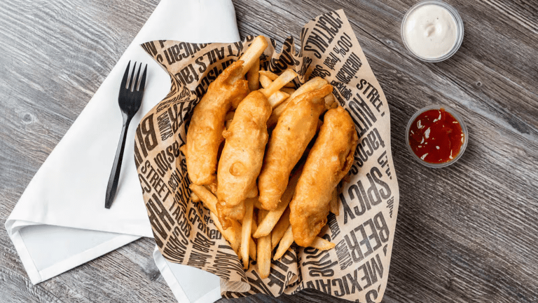 topdown view of fish and chips with a side of ketchup and cream.