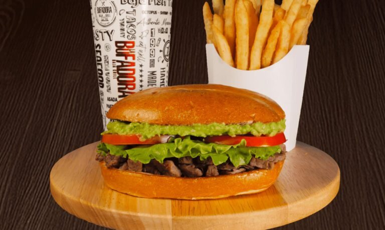 a torta on a table with french fries and a fountain drink on the side.