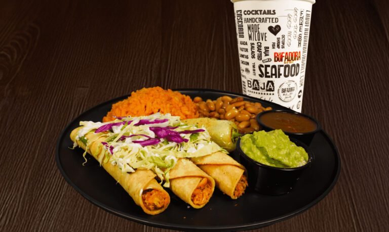 3 rolled chicken taquitos loaded with vegetables and condiments on a plate along with rice, beans, salsa, guacamole, a pepper, and a fountain drink.