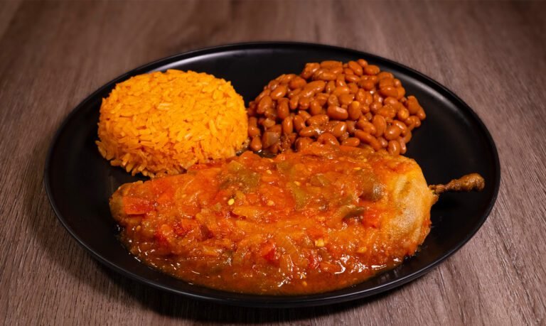 plate with chile relleno, rice, beans, and a fountain drink on the side