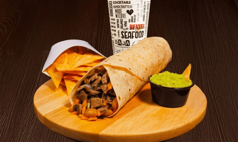 burrito with a side of tortilla chips, guacamole, and a fountain drink