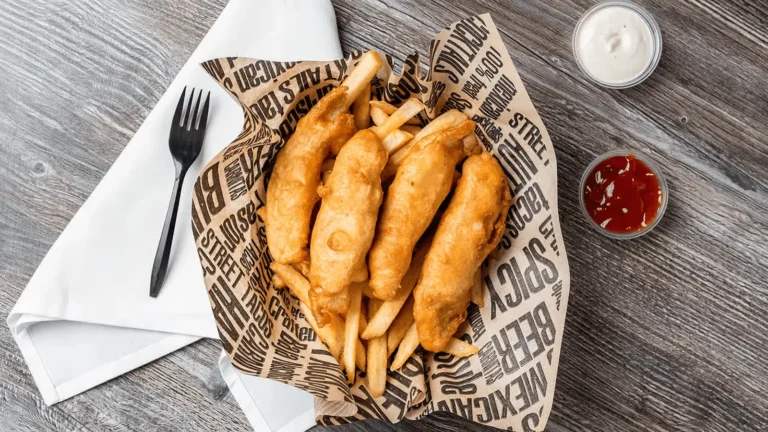 topdown view of fish and chips with a side of ketchup and cream.