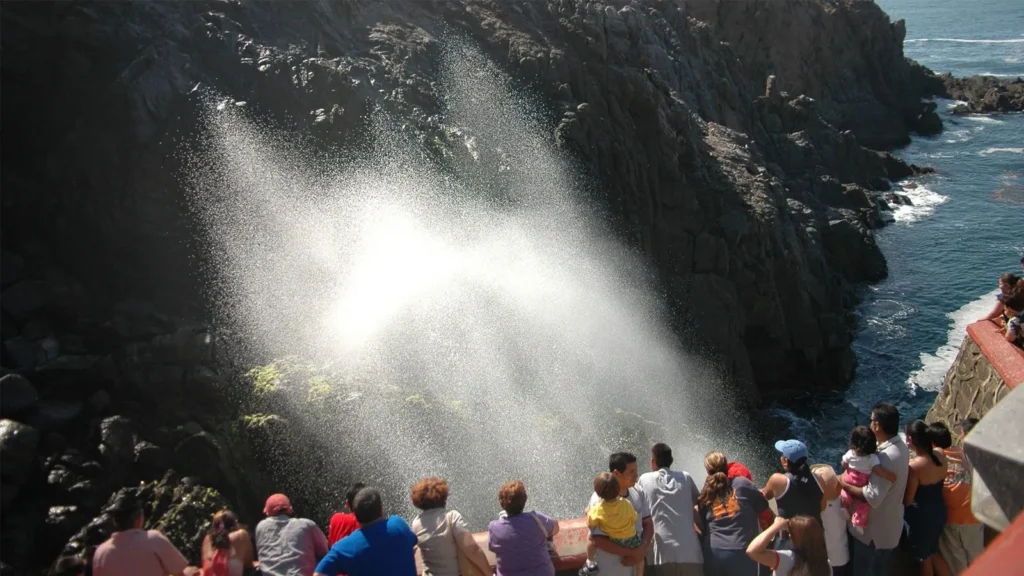 a hillside in mexican displaying water crashing and splashing up against the hill